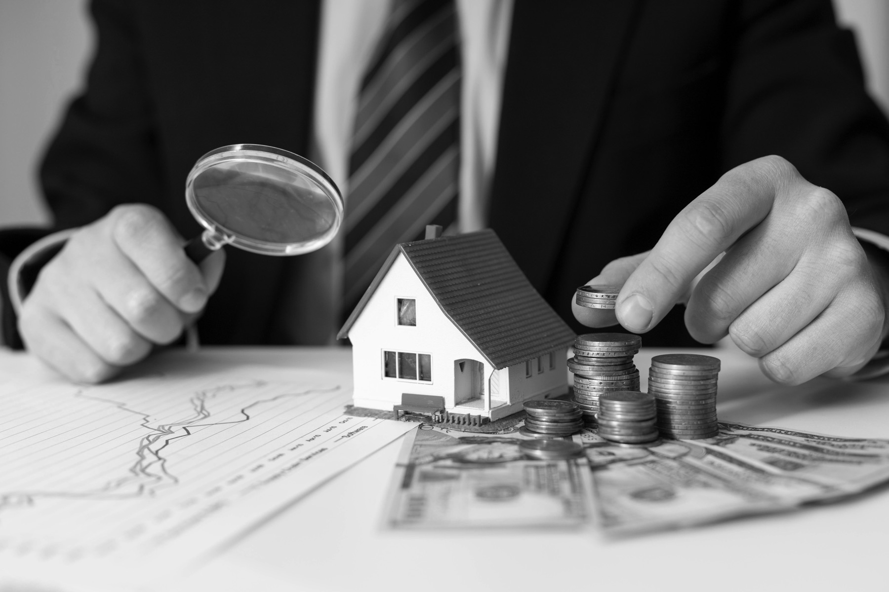 Adviser reviewing property investment with model house and coins